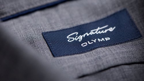 Neues Logo OLYMP Signature auf einem Hemdskragen