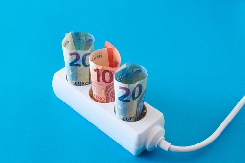 Mehrfachsteckdose mit Euroscheinen vor blauem Hintergrund