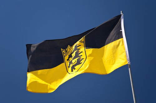Eine baden-württembergische Fahne weht vor blauem Himmel.