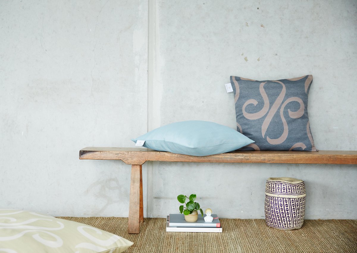 Auf einer Bank liegen ein hellblaues und ein graues Kissen mit Logo von Darling Little Place.