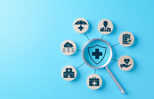 Lupe fokussiert auf Schild mit medizinischem Kreuz, umgeben von Symbolen, medizinische Versorgung, Krankenversicherung, Gesundheitsdienste, Schutz, Abdeckung,
