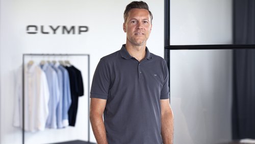 Stefan Klieber im Büro vor einem Kleiderständer mit Olymp-Hemden