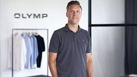 Stefan Klieber im Büro vor einem Kleiderständer mit Olymp-Hemden