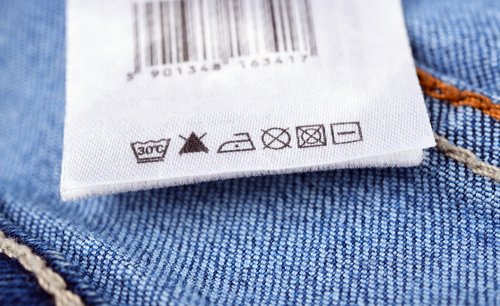 Nahaufnahme eines Stoff-Pflegeetiketts, das auf blauen Jeans genäht ist.