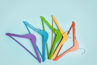 Fünf verschieden farbige Kleiderbügel auf hellblauem Hintergrund