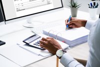 Mann prüft Zahlen mit einem Taschenrechner