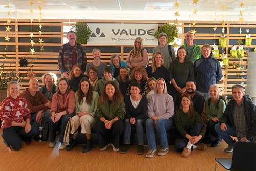 Jubilare vor einer Wand mit Aufschrift VAUDE