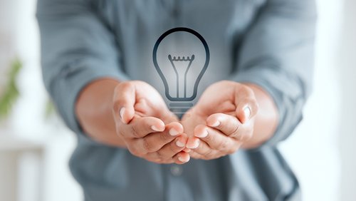 Eine Person hält die Hände zu einer Schale und darin schwebt eine Glühbirne.