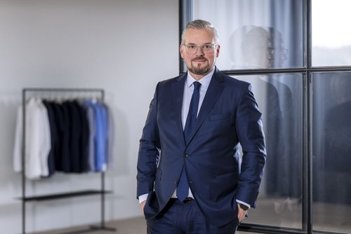 COO Johann Trischberger vor Olymp-Hemden in einem Büro