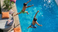 Zwei Kinder springen in einen Pool