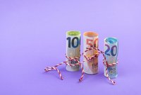 Rollen mit 100-, 50- und 20-Euro-Geldscheinen, isoliert auf hellviolettem Hintergrund