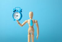 Person hält Uhr in der Hand auf blauen Hintergrund