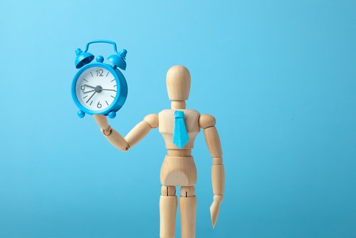 Person hält Uhr in der Hand auf blauen Hintergrund