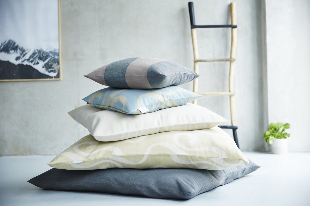 In einem stilvollen Interieur liegt ein Stapel mit Darling Little Place Kissen in unterschiedlichen Farben und Mustern.