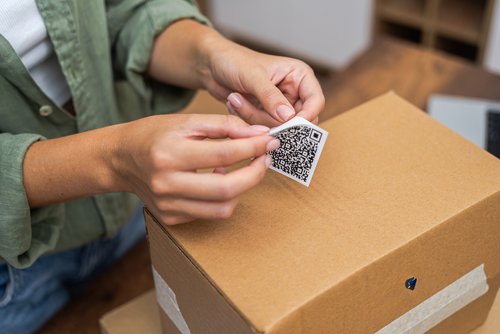 Frau klebt Barcode auf Verpackung