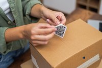 Frau klebt Barcode auf Verpackung