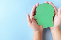 Menschliche Hand, die grüne Kopfprofilsilhouette mit Kopierraum hält. Grüner und nachhaltiger Lebensstil, gesundes Wohlbefinden und psychisches Gesundheitskonzept.