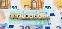 Holzwürfel mit Text "Elternzeit" liegen auf Euroscheinen