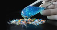 Reagenzglas mit Wasser und Mikropartikeln vor schwarzem Hintergrund