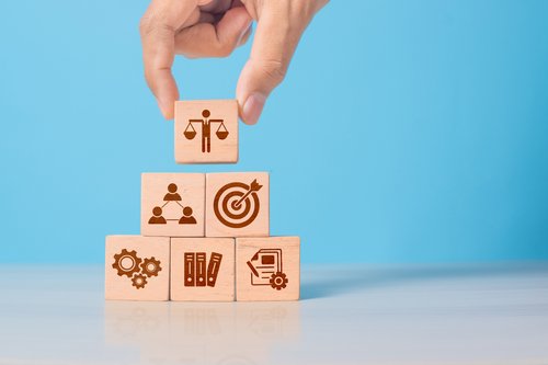 Holzwürfel mit Ethiksymbol in der Hand. Steht für unternehmerische Verantwortung
