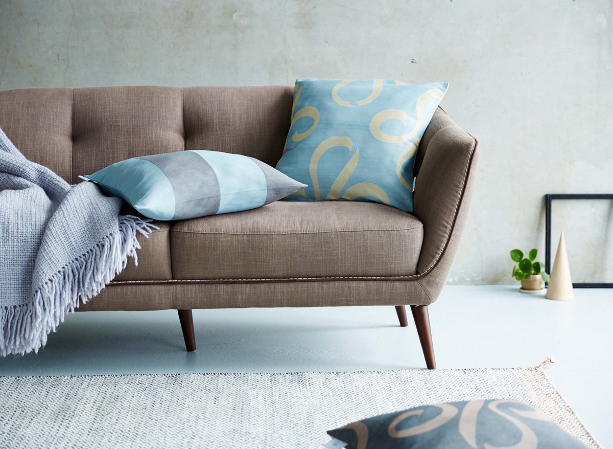 Auf einem grau-beigen Sofa liegen hellblaue gemusterte Kissen von Darling Little Place. 