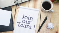 Block mit Join Our Team neben Stift und Kaffeetasse