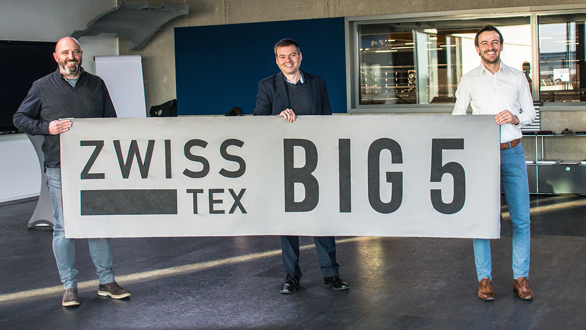 Drei Männer halten ein Banner mit der Beschriftung "zwisstex Big 5"