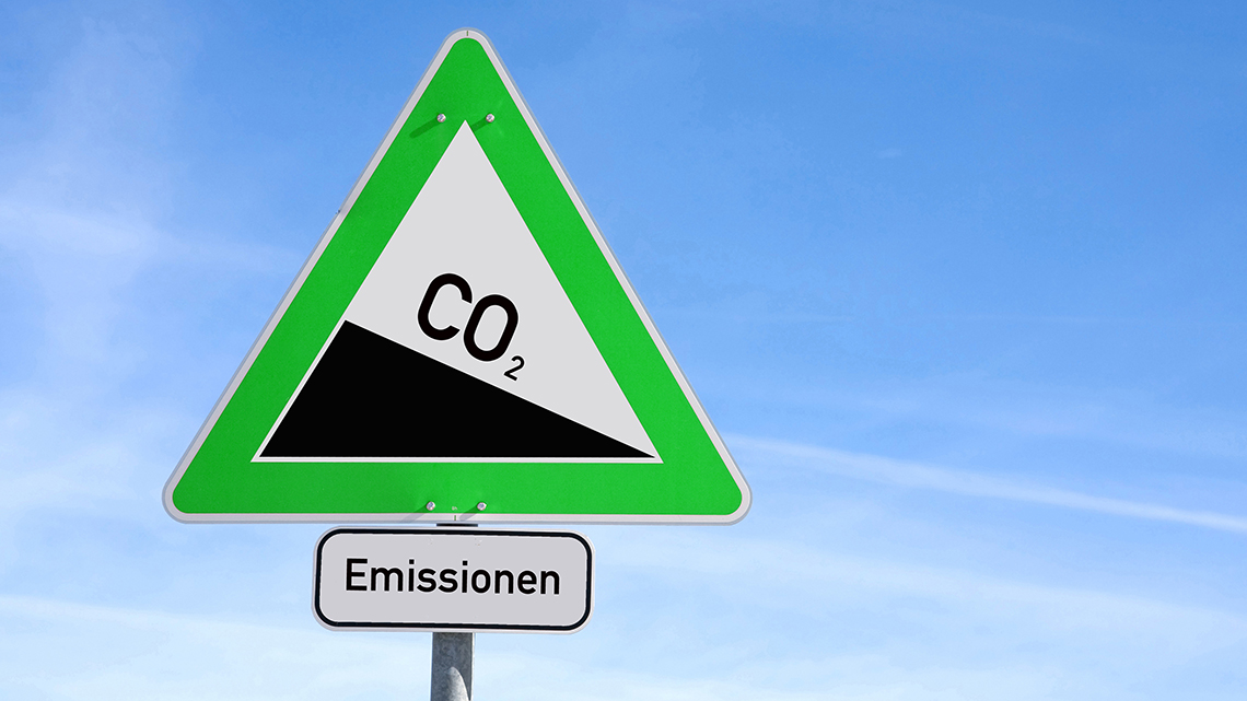 Ein Schild mit einem grünen Rand zeigt abfallende CO2-Emissionen an. 