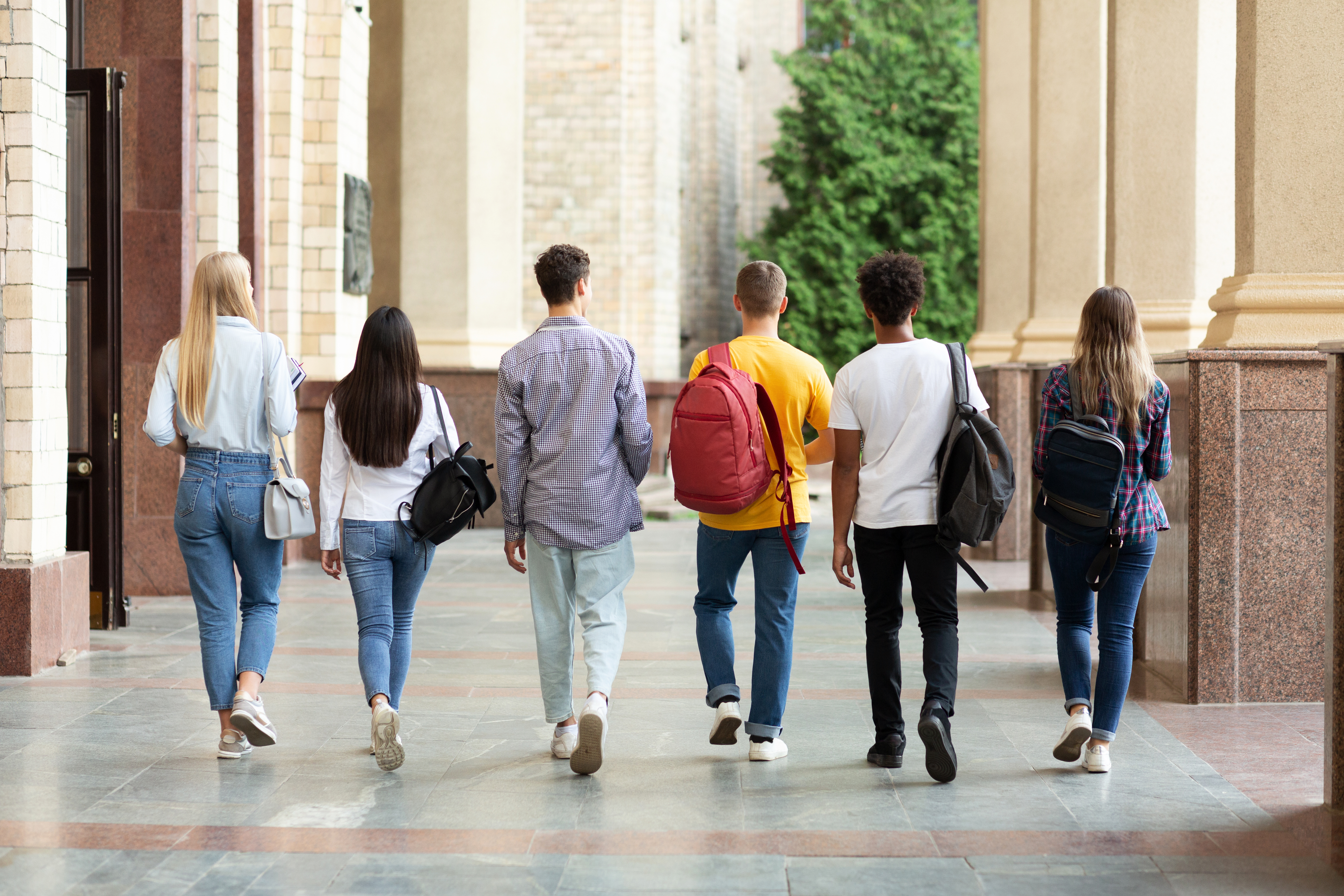 Eine Gruppe von Studierenden läuft auf dem Campus einer Hochschule nebeneinander. 