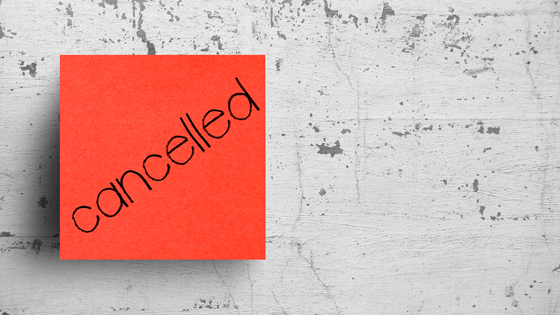 Auf einer grauen Betonwand ist eine rote, quadratische Notiz mit der handschriftlichen Beschriftung "cancelled" zu sehen.