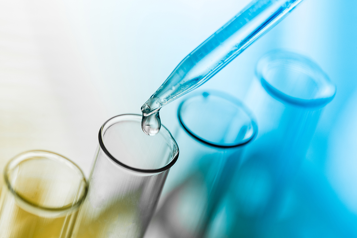 Pipette tropft Flüssigkeit in eins von mehreren Reagenzgläsern