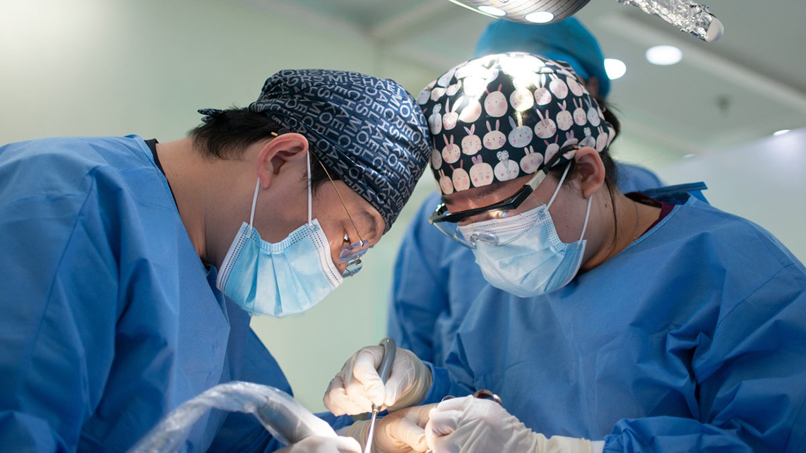 Zwei Chirurgen beugen sich im OP über Patient