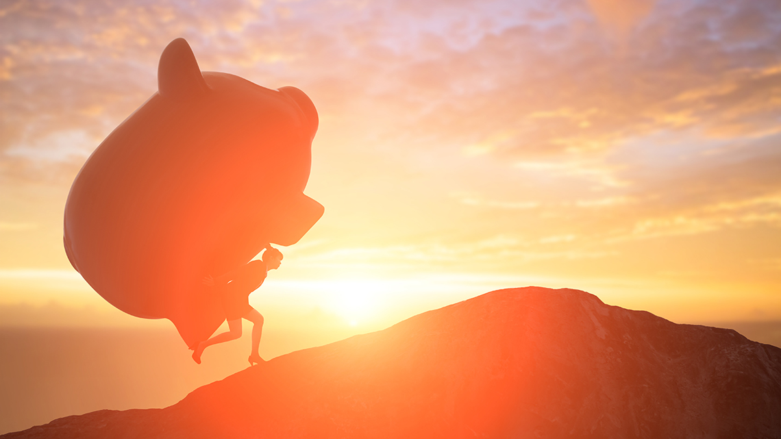 Frau trägt Sparschwein bei Sonnenuntergang einen Berg hoch.