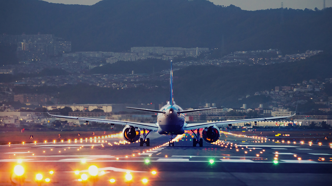 Ein großes Flugzeug landet in der Abenddämmerung am Osaka-Itami International Airport, Japan.