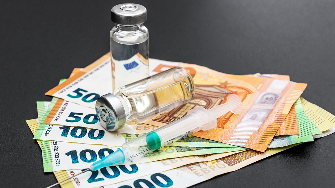 Zwei Impfampullen stehen neben einer Spritze auf mehreren Eurogeldscheinen