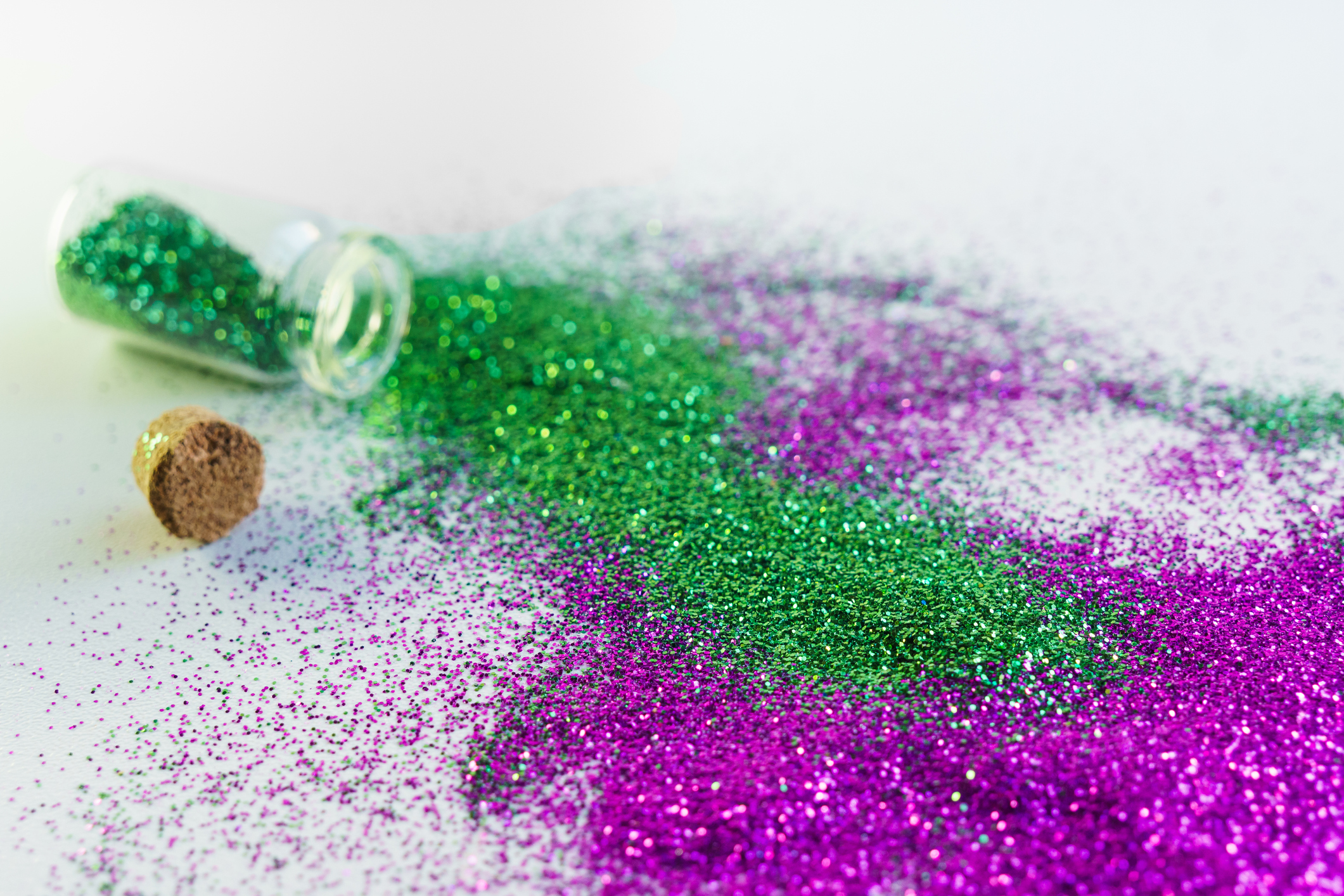 Flasche mit grünem und rosa Glitzer auf weißem Hintergrund. Glitzer ist in Europa verboten Konzept.