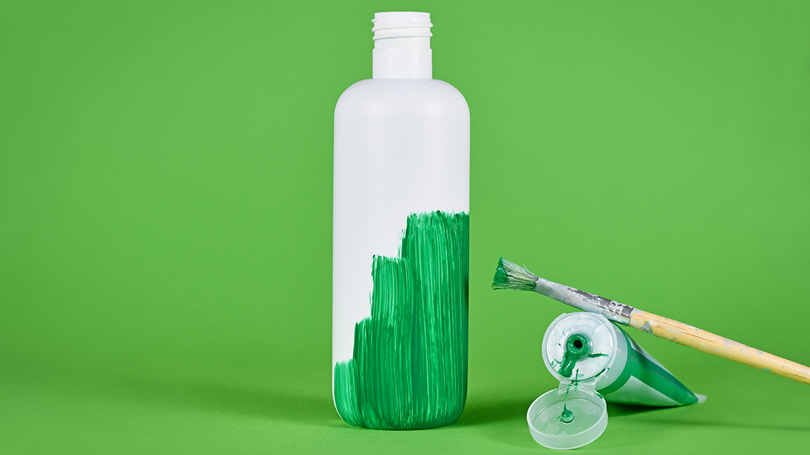 Vor einem grünen Hintergrund steht eine weiße Flasche, die grün angemalt wird.