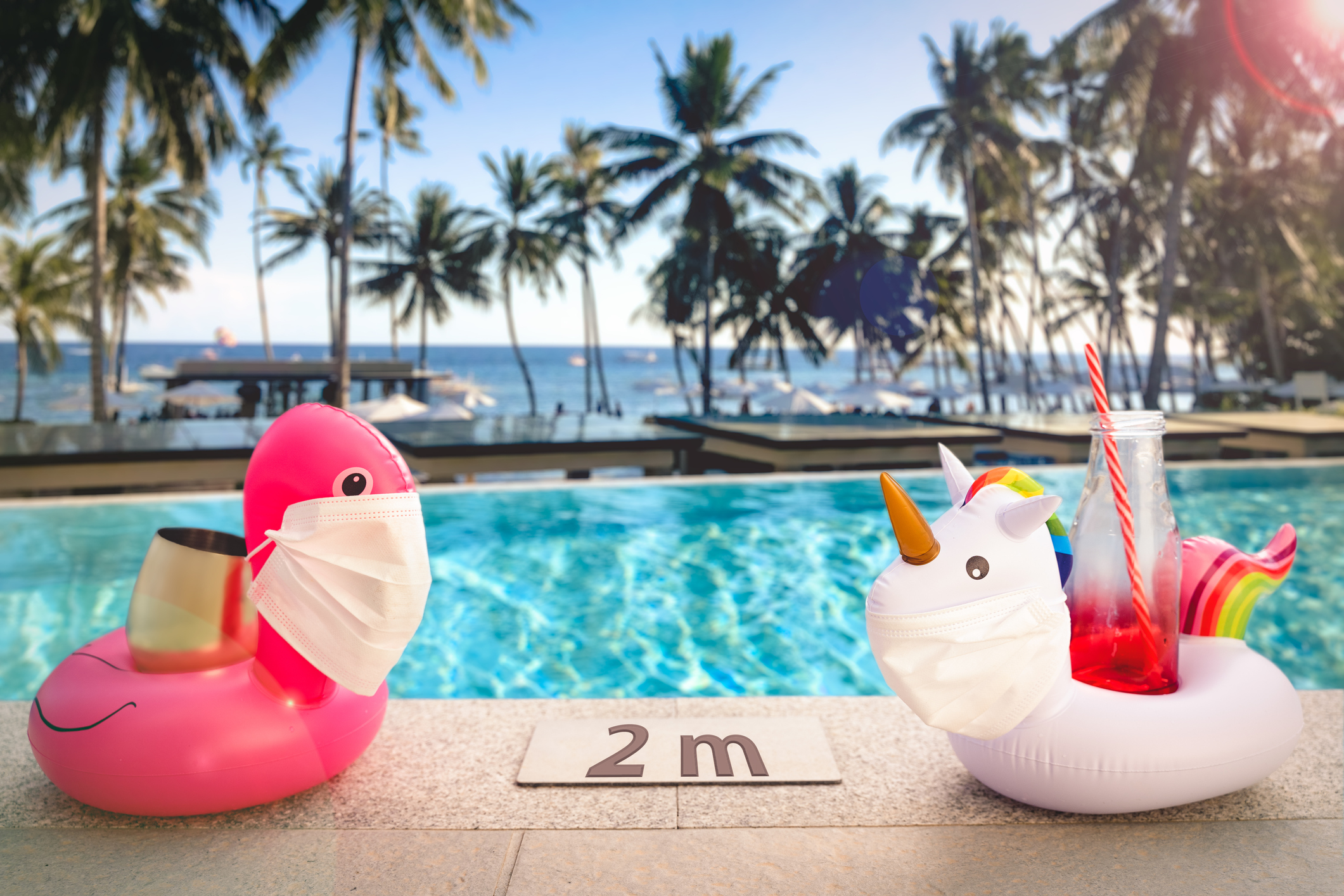 Zwei aufblasbare Tiere mit medizinischen Masken am Pool