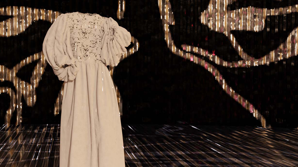 Vor einem von hellen Schnörkeln durchzogenen dunklen Hintergrund ist ein elegantes beiges Kleid animiert.