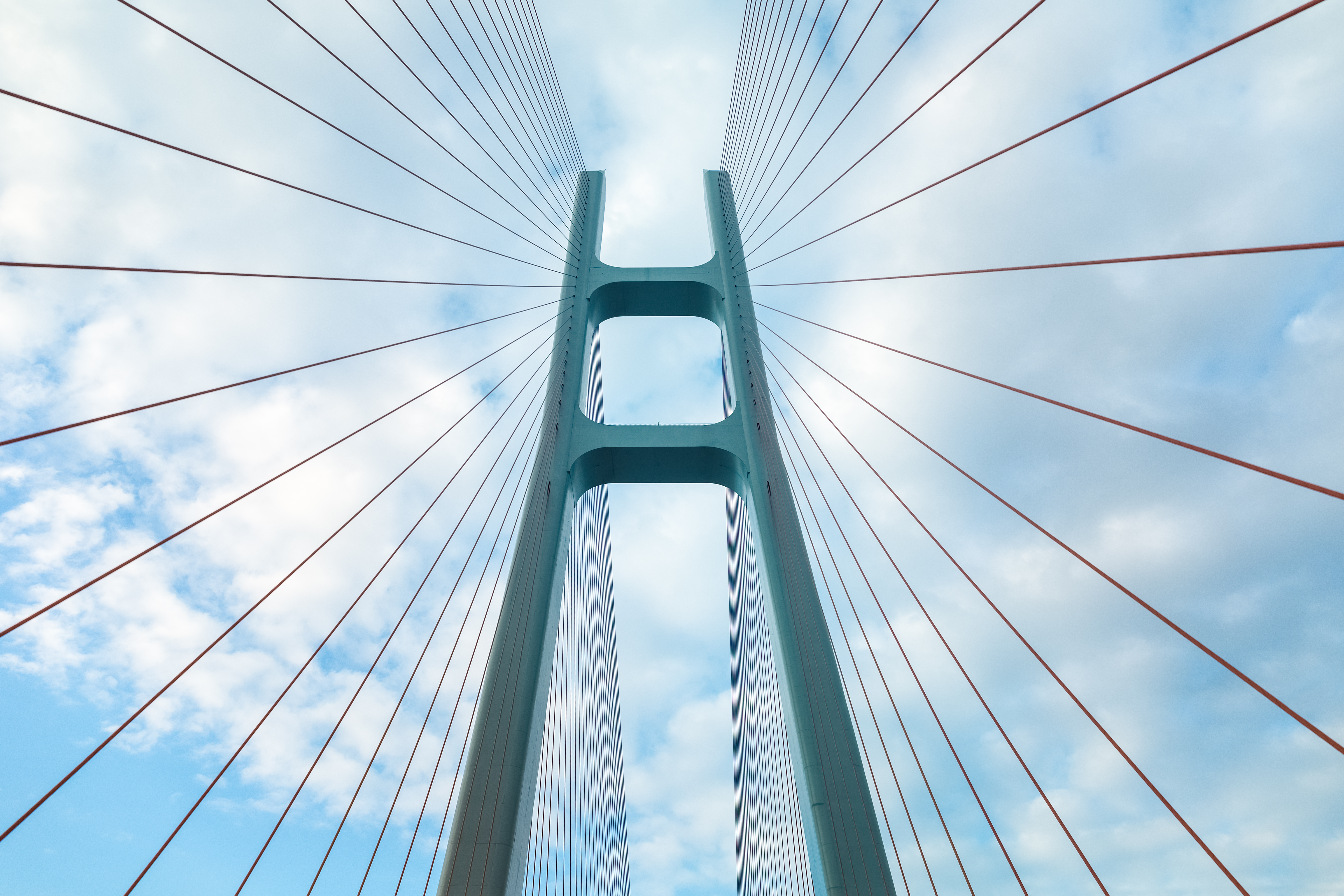 Brücke wird von Seilen getragen und wird von unten in den Himmel fotografiert.