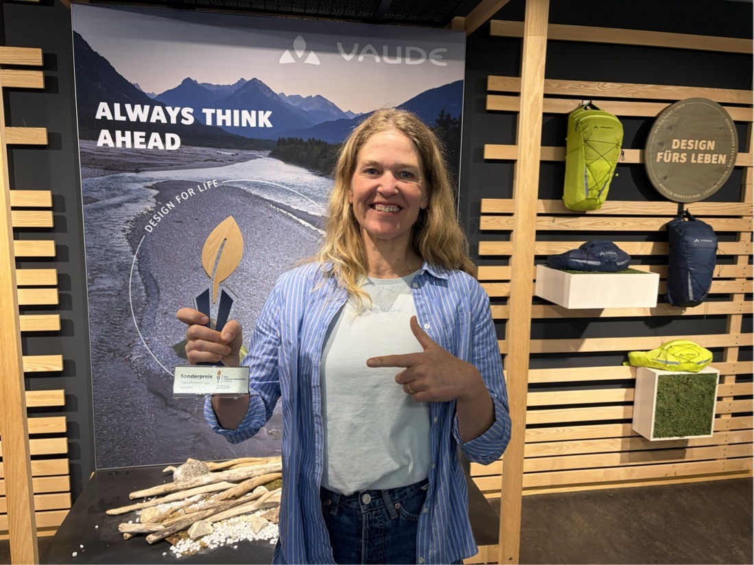 Frau von Dewitz mit Preis in der Hand vor einer Stellwand mit VAUDE-Informationen