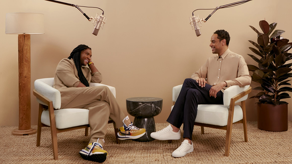 Raven Smith sitzt gemeinsam mit Law Roach, seinem ersten Gast in der neuen Podcast-Serie Behind the BOSS, in entspannter Atmosphäre in einem Podcast Studio.