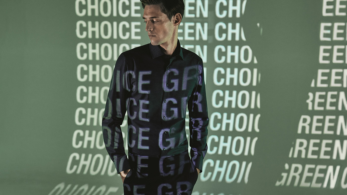 Mann steht vor Wand, an die mit einem Projektor mehrfach die Wörter Choice Green geworfen werden.