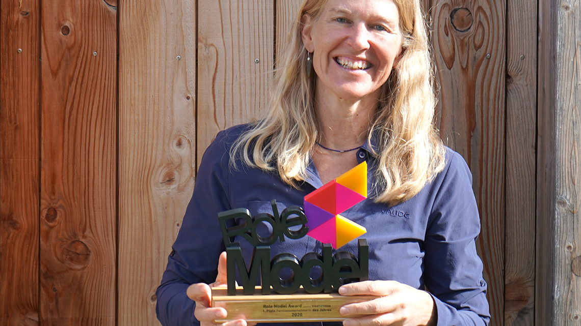 VAUDE-Geschäftsführerin Antje von Dewitz hält den Role Model Award lachend in die Kamera.