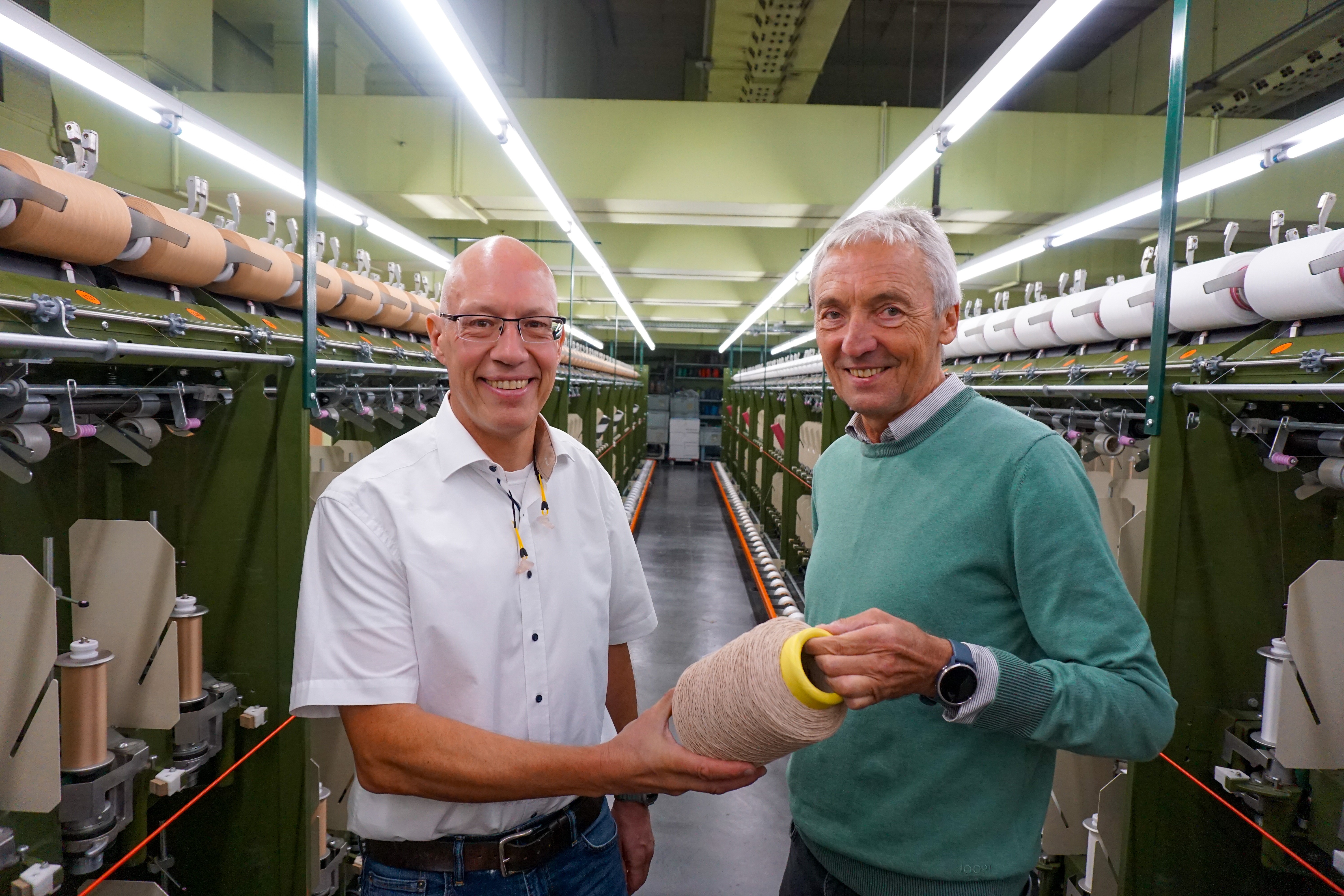 Michael Schmidt und Hans-Peter Mauch bei der symbolischen Spulenübergabe in der Produktion.