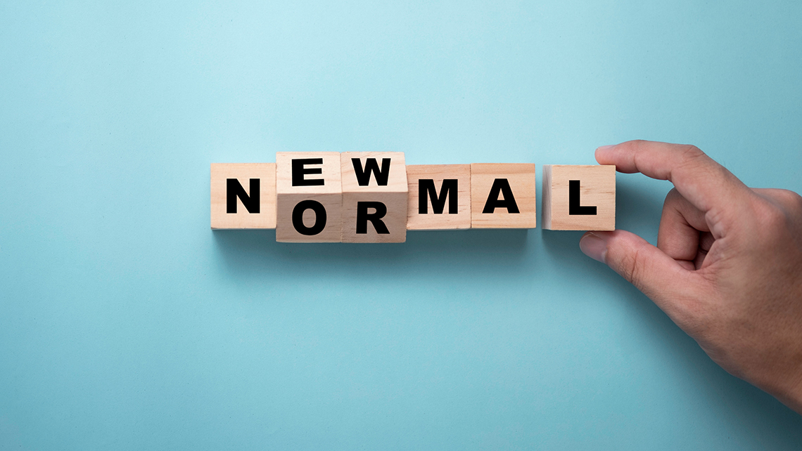 Vor einem türkis-leuchtenden Hintergrund verschiebt eine Hand Würfel mit den Buchstaben New Normal.