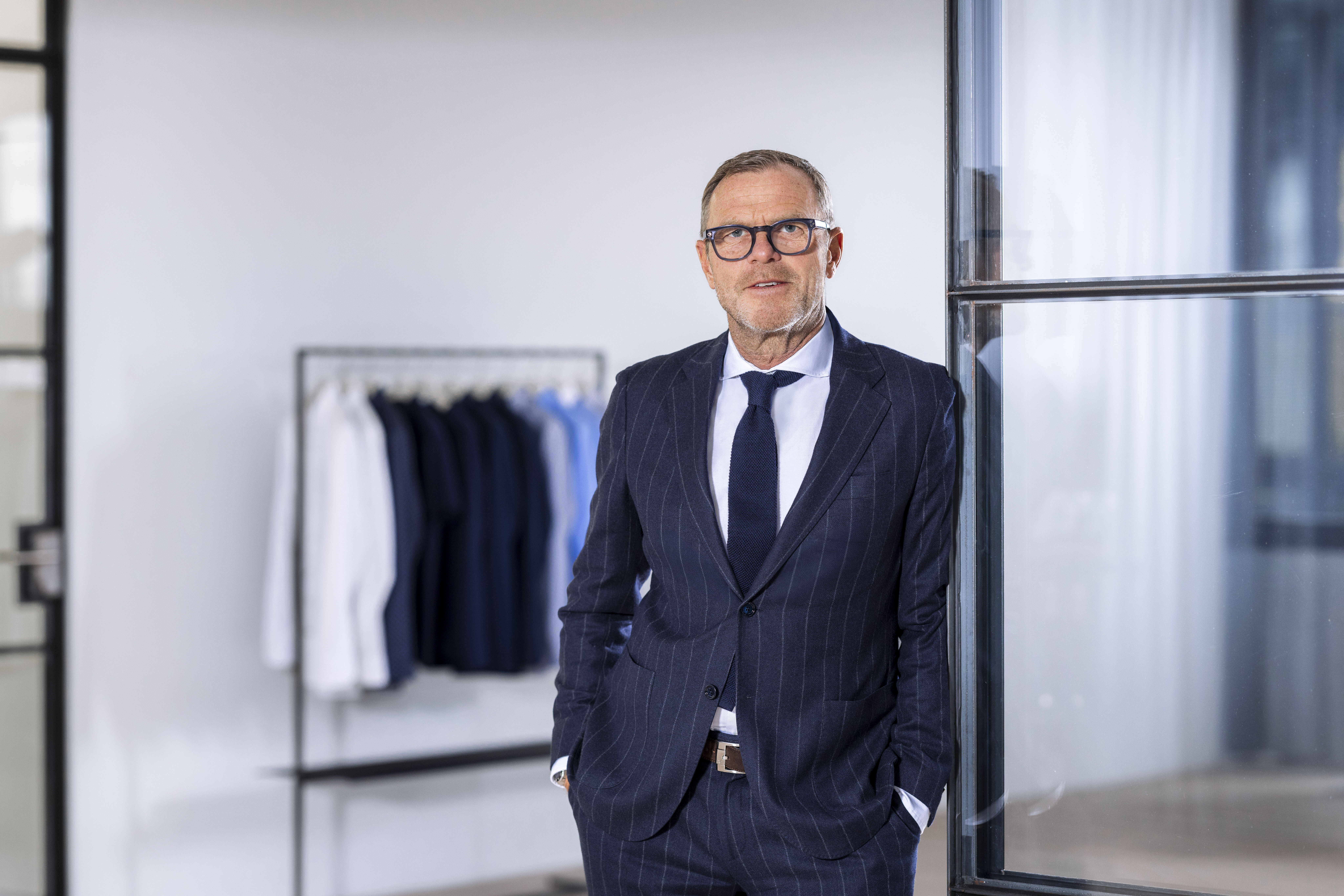 Mark Bezner vor einer Kleiderstange mit Blusen und Hemden