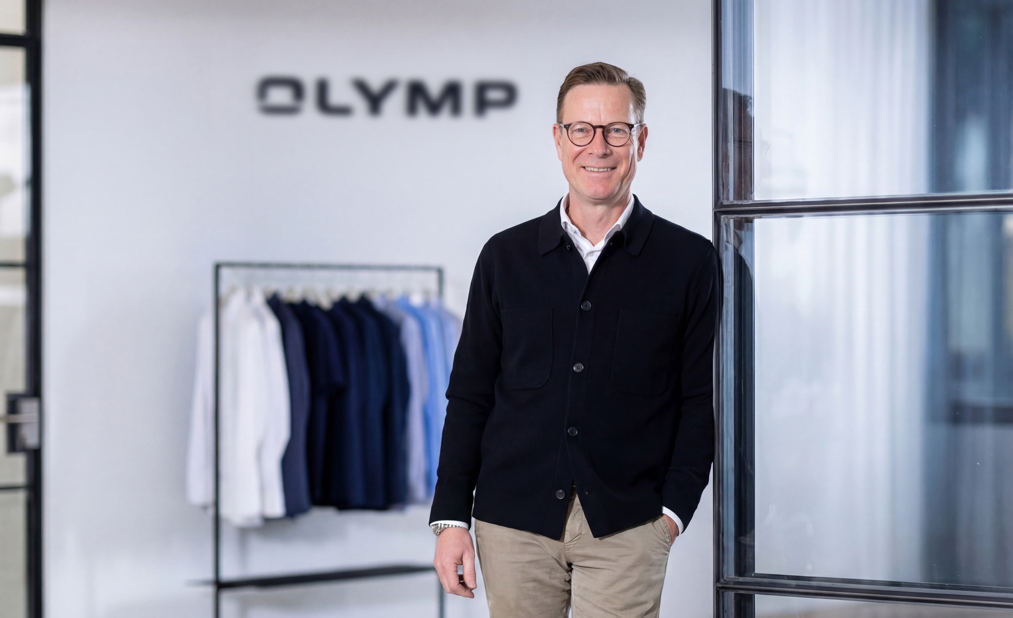 Peter Hoever vor einer weißen Wand mit OYMP-Aufschrift