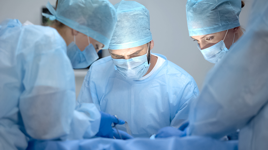 Chirurgenteam beugt sich über Patient auf OP-Tisch