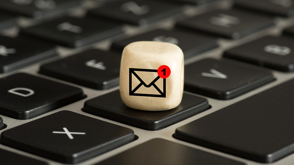 Kleiner Holzwürfel mit Briefumschlagsymbol liegt auf einer Laptoptastatur
